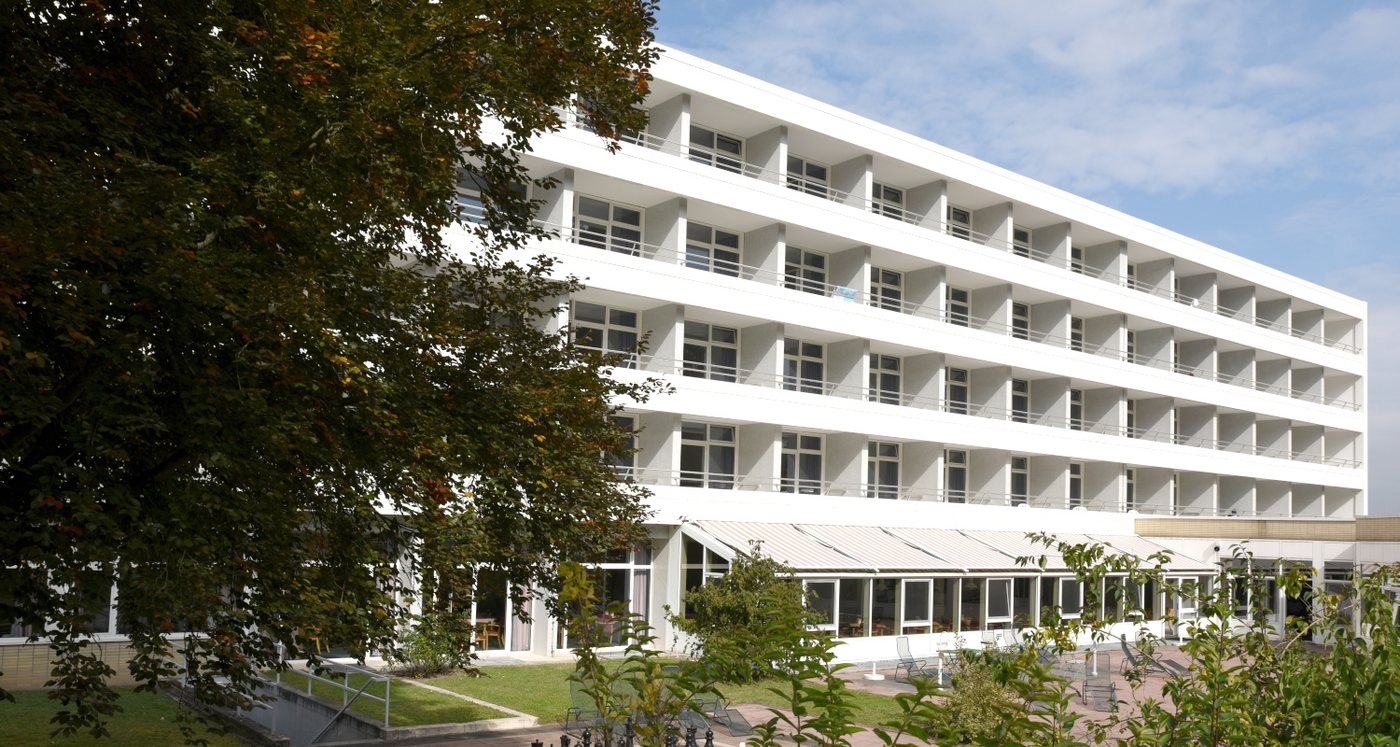 Montanus-Klinik Bad Schwalbach: weißes Klinikgebäude mit Balkonen und Terrasse im Grünen